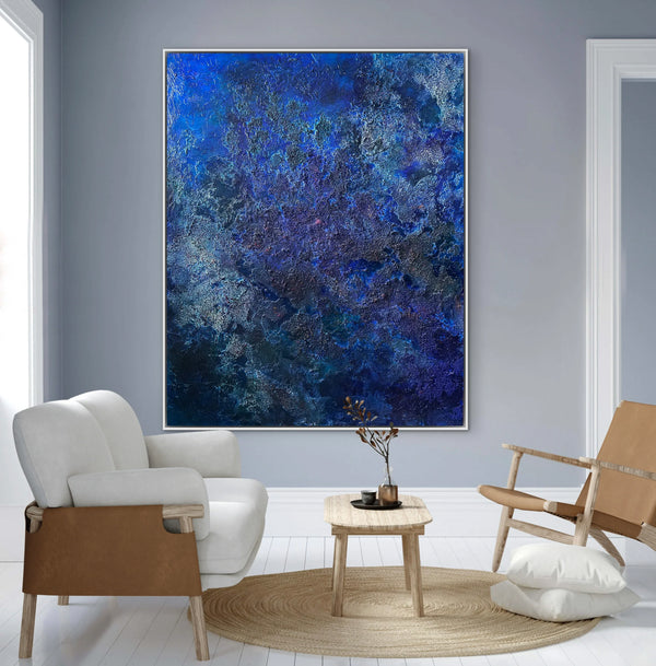 Living room with a large abstract blue painting on the wall, two chairs, and a small table.