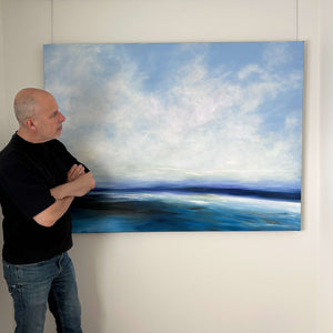 Guy Trimquet with ;arge painting of a blue sky with clouds