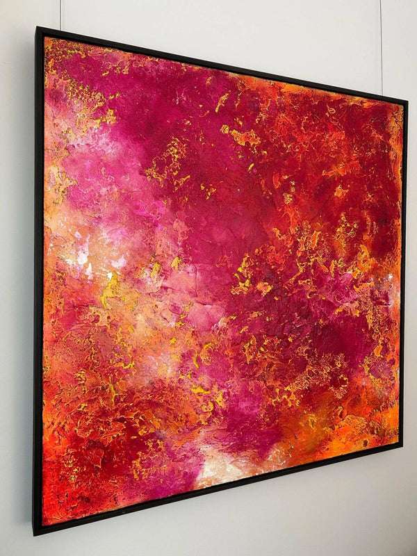Abstract art piece with pink, orange, and gold colors on a white wall.