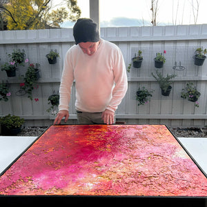Guy Trinquet inspecting textured red orange painting