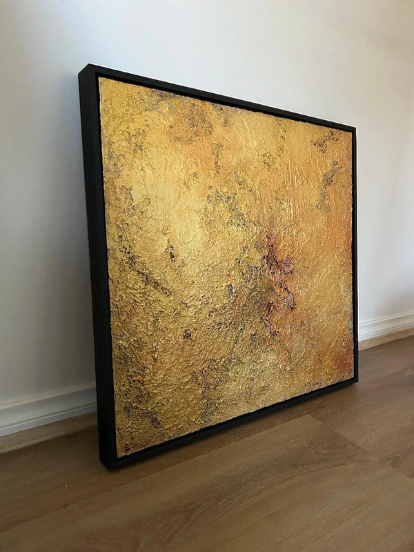 Framed textured gold artwork on a white wall